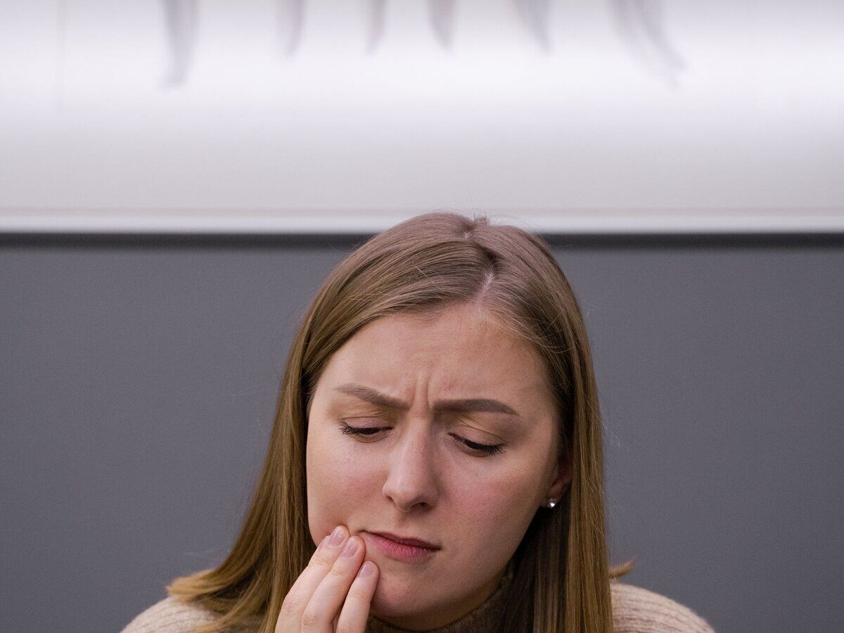 Personne ressentant une douleur dentaire soudaine, la main sur la joue